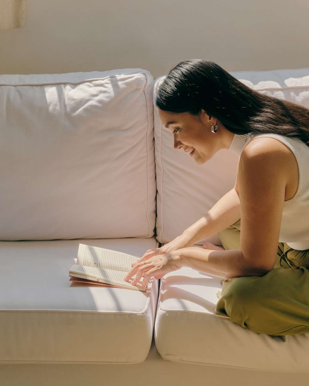 Female entrepreneur on a white couch reading a book about purpose-driven business